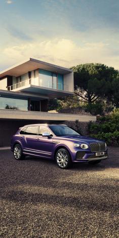 Side angled view of Bentley Bentayga Mulliner in Tanzanite purple colour, parked outside a home