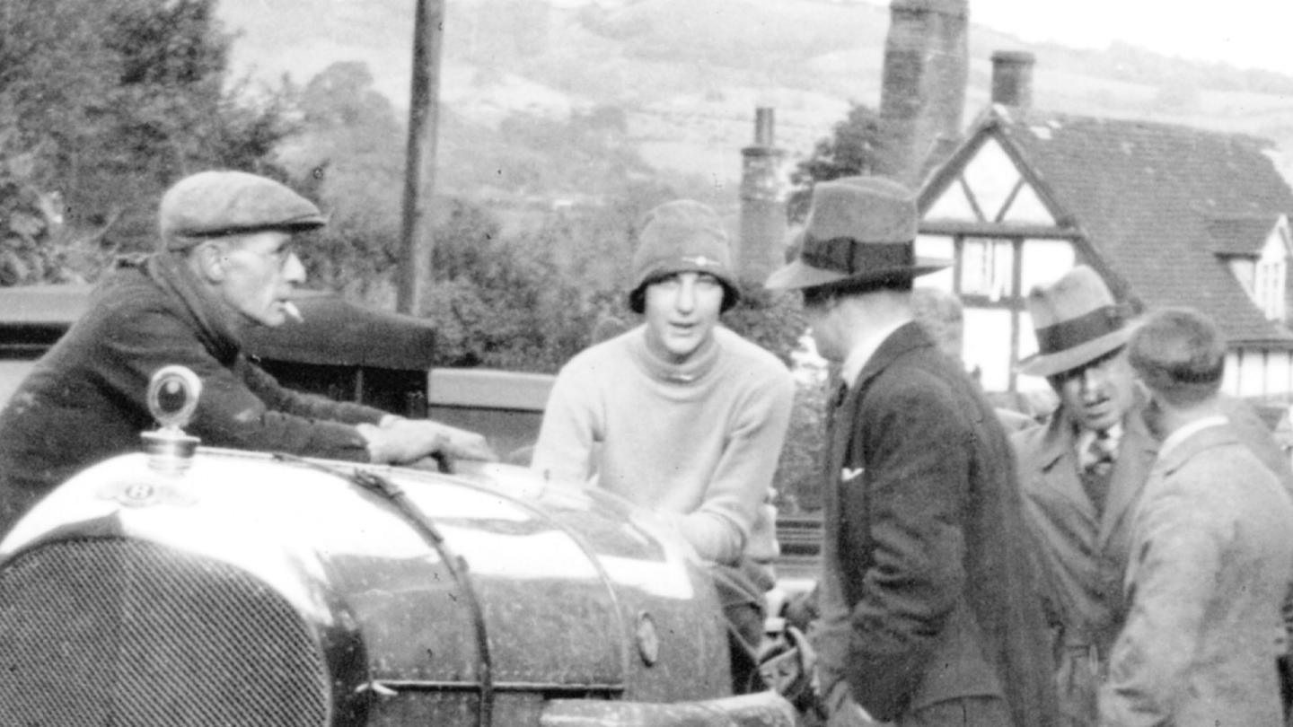 May Millington sat on top of a racing Bentley discussing the race ahead with her pit crew