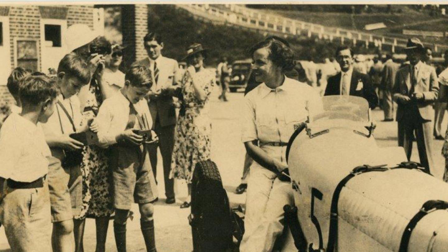 Margaret Allen engaging with young fans at the Whistsun Long Handicap race while leaning on her Bentley 6 1/2 Litre