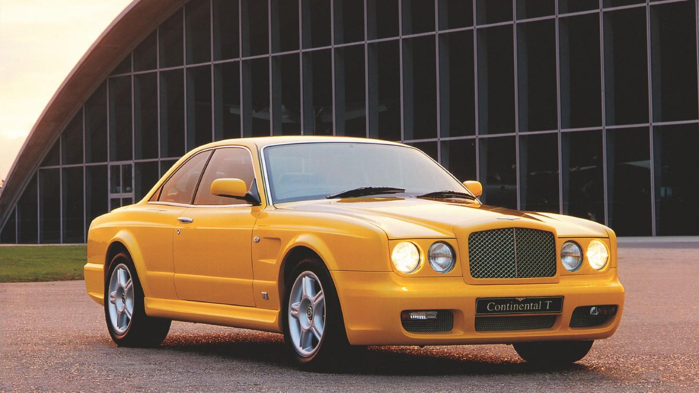 A front three quarter of a bright yellow Continental T parked outside a building