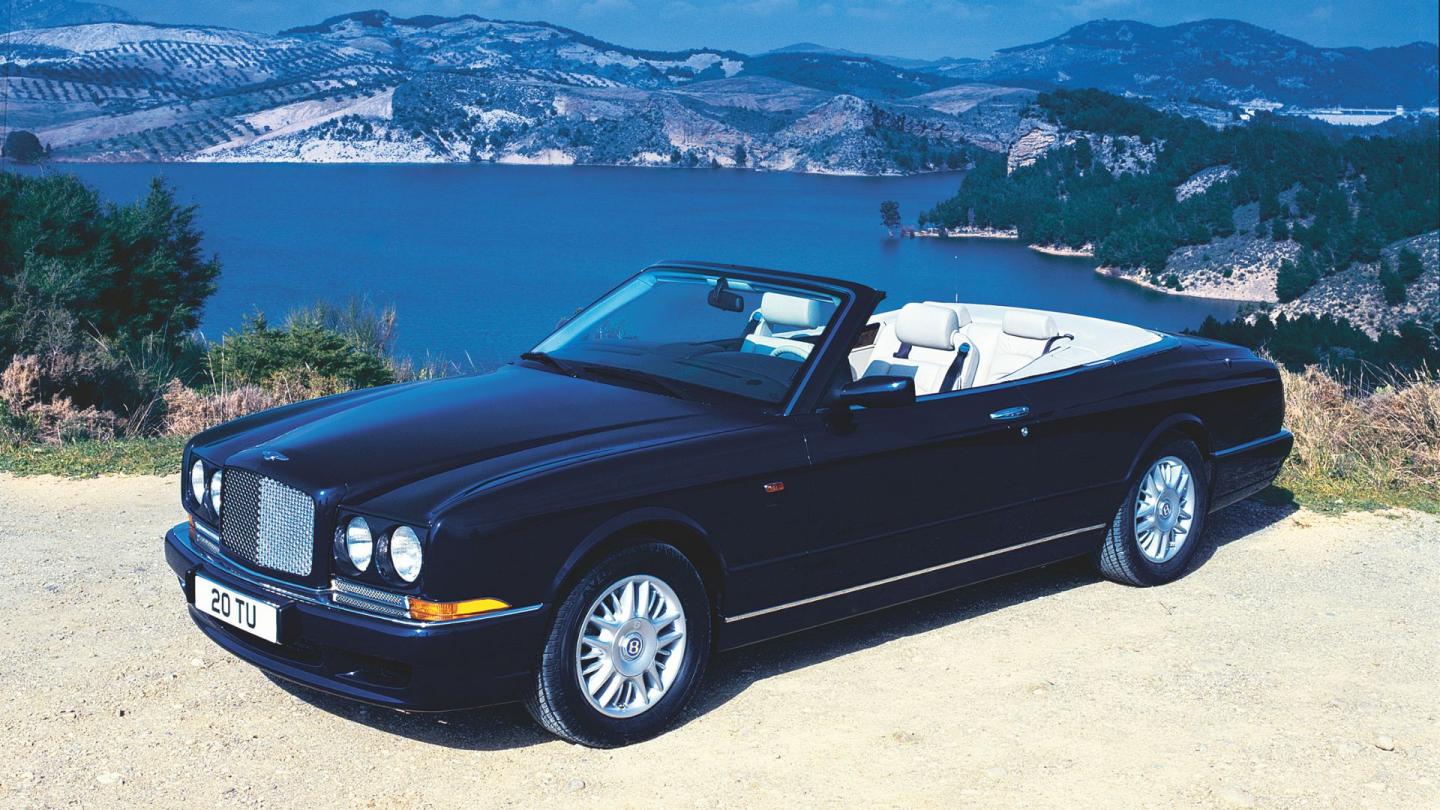 A front three quarter of the open top convertible Bentley Azure with a cream white interior and a blue exterior paint