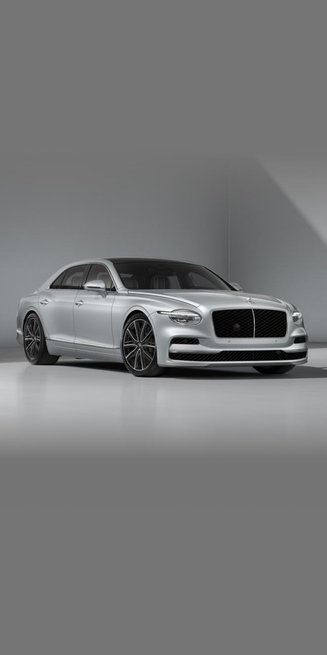 Front three-quarter of the Bentley Flying Spur in Moonbeam showing the headlights and 21" Ten Twin Spoke Wheel in Dark Grey Painted and Bright Machined finish.