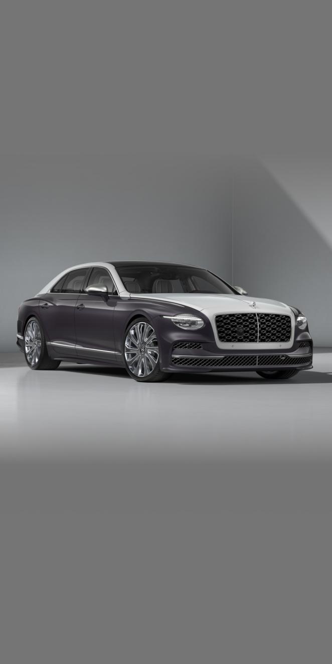 Front three-quarter of the Bentley Flying Spur Mulliner in Ice / Grey Violet showing the headlights, Carbon Styling Spec and 22" Mulliner Grey Painted & Polished wheel.
