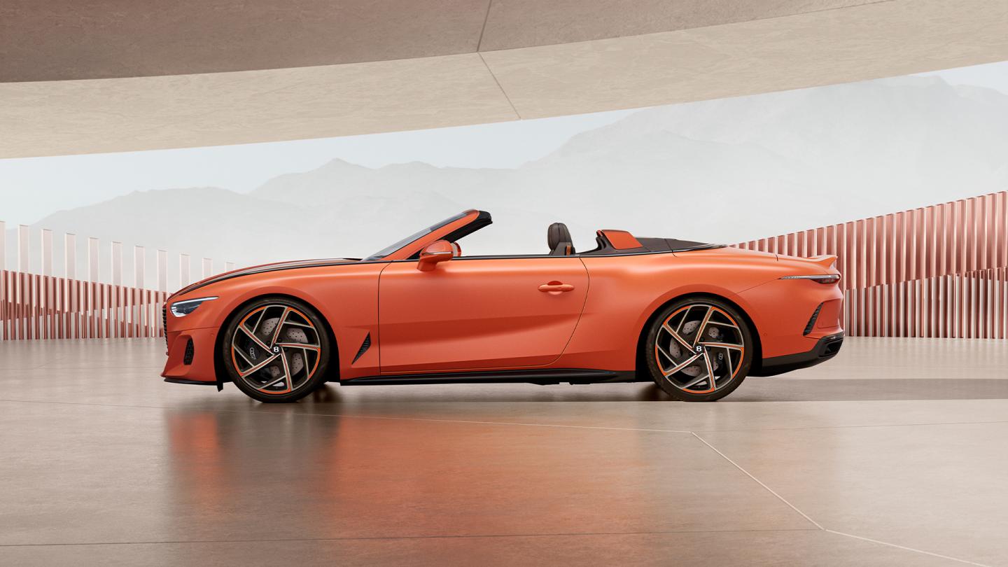 A side profile shot of the convertible Batur model, featuring a vibrant matte orange exterior paint and bespoke colour matched wheels