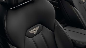 Bentey Bentayga EWB interior view for rear passenger seats featuring Bentley emblem in Linen contrast stitching over seats in Beluga hide 