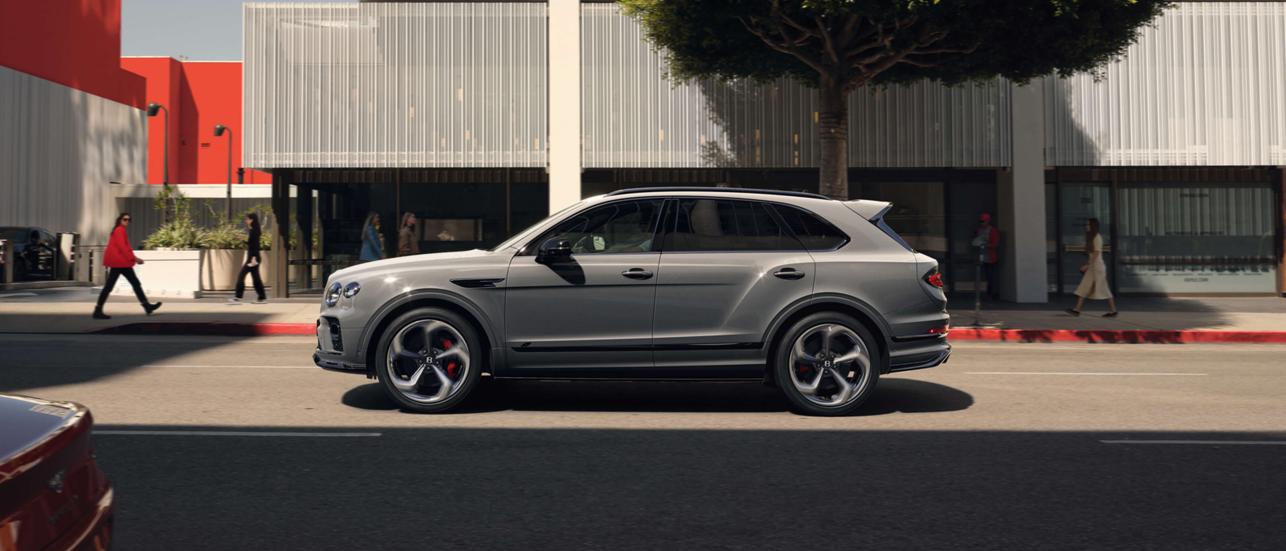 Bentley Batur side angled view parked outside Bentley Boutique, featuring directional 22 inch Alloy wheels and Bentley Branded Red brake callipers.