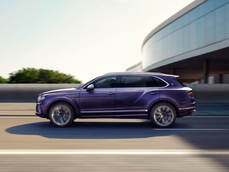 Bentley Bentayga EWB Mulliner side view in Tanzanite Purple with chrome accents driving along a highway.