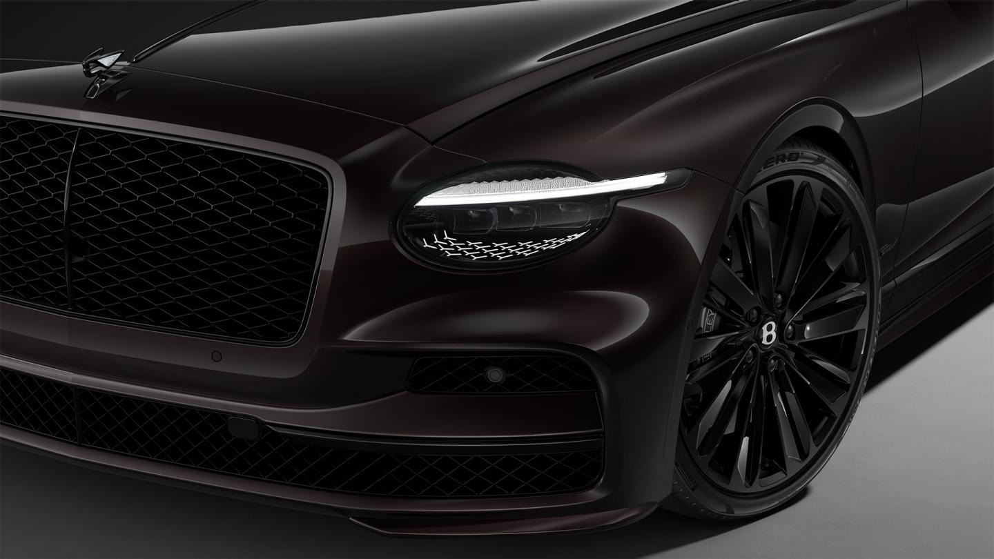 Front three-quarter close-up of the Bentley Flying Spur Speed in Black Velvet showing the headlights and 22" Speed Wheel painted in black.