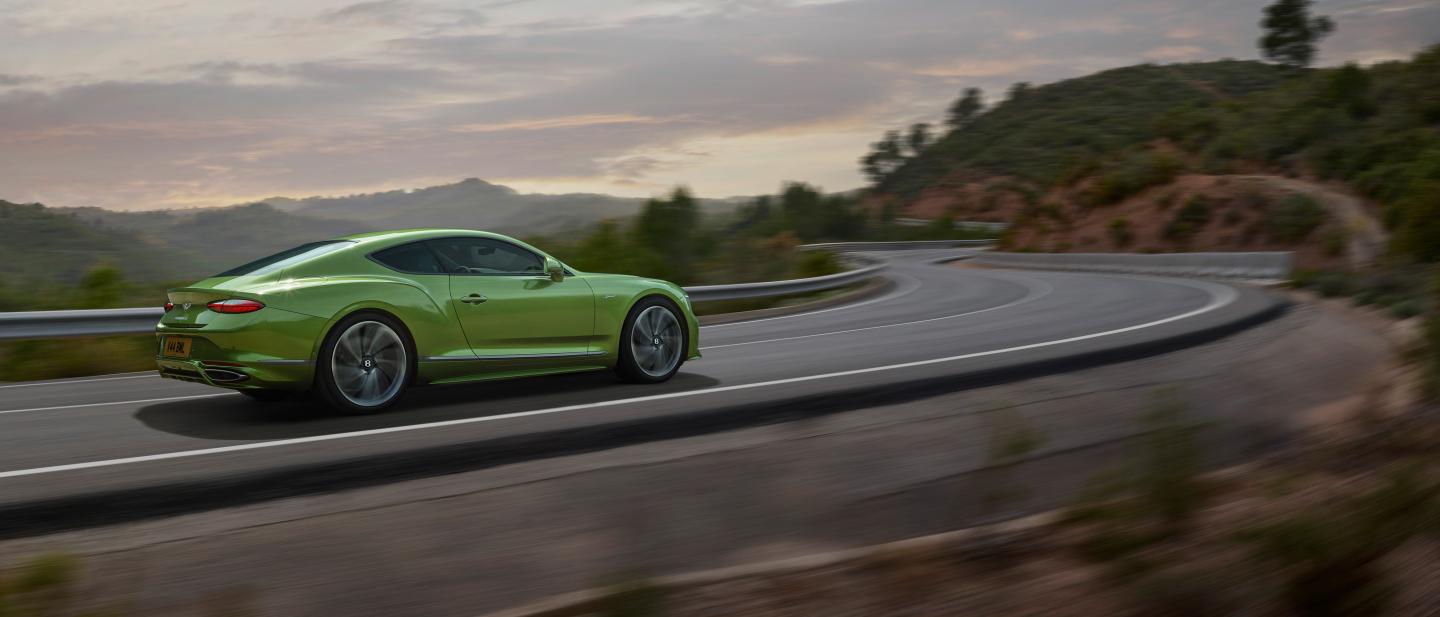 The new hybrid Continental GT Speed in Tourmaline Green driving in a rural environment