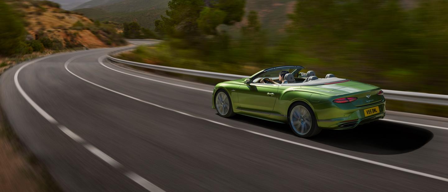 The new hybrid Continental GTC Speed in Tourmaline Green driving in a rural environment
