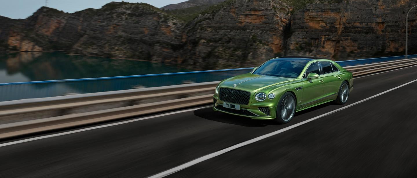 The new hybrid Flying Spur Speed in Tourmaline Green driving in a rural environment